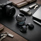 CTRL8 T2 over-the-ear earbuds with UNBLOQ technology placed on a wooden desk alongside a camera and keys
